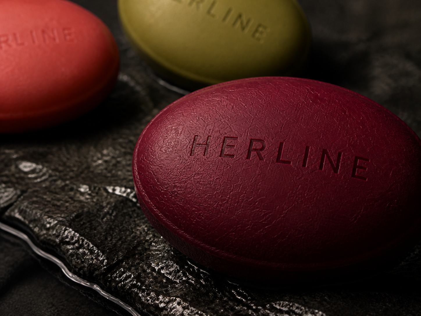 湿润深色石材上的 HERLINE 定制香皂近景